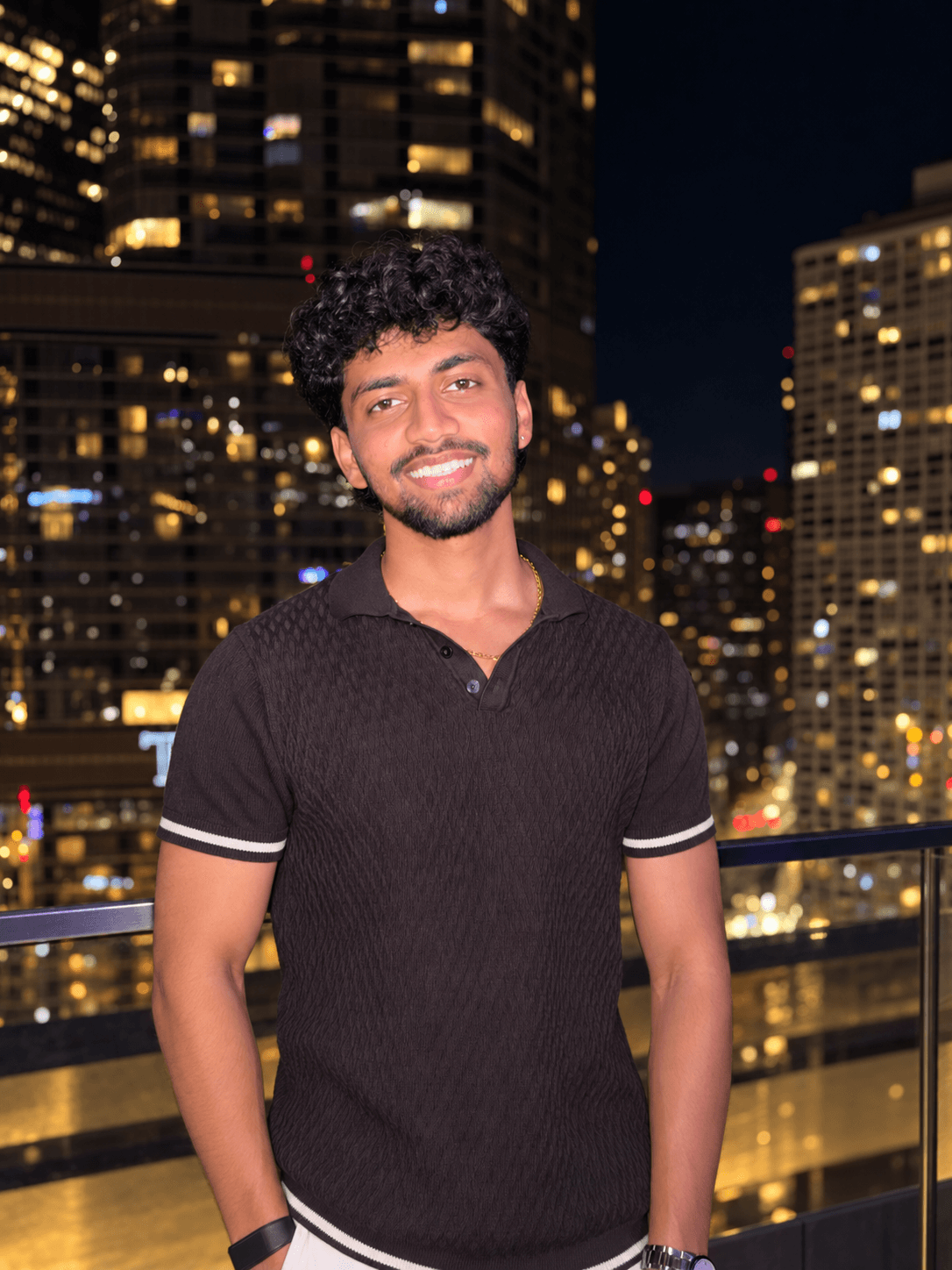 Mukhil Baskaran smiling against a softly lit city skyline at night